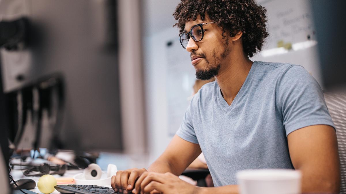 Male developer with a beard typing on computer keyboard