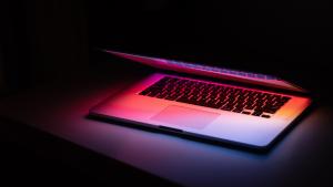 Devices - A laptop halfway open, on a darkened table, with a faint pink glow om-kamath-eL_FERodaT4-unsplash.jpg