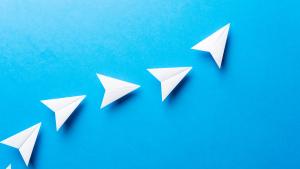 Paper airplanes forming a line on blue background