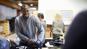 Black man packing a backpack at workplace