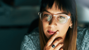 woman with glasses looking thoughtfully at a computer screen