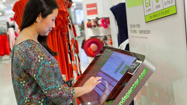 An M&S shopper browsing a screen in-store for product.