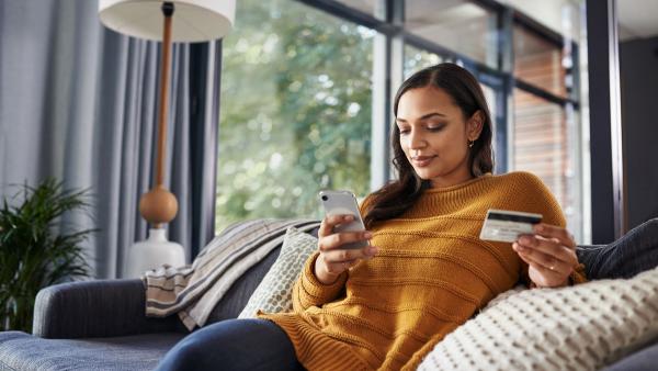 Person shopping online with mobile phone and holding credit card