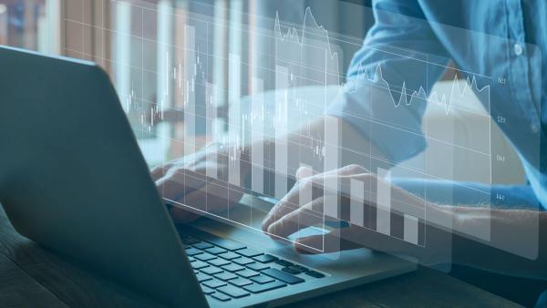 Hands typing on laptop with bar chart superimposed 